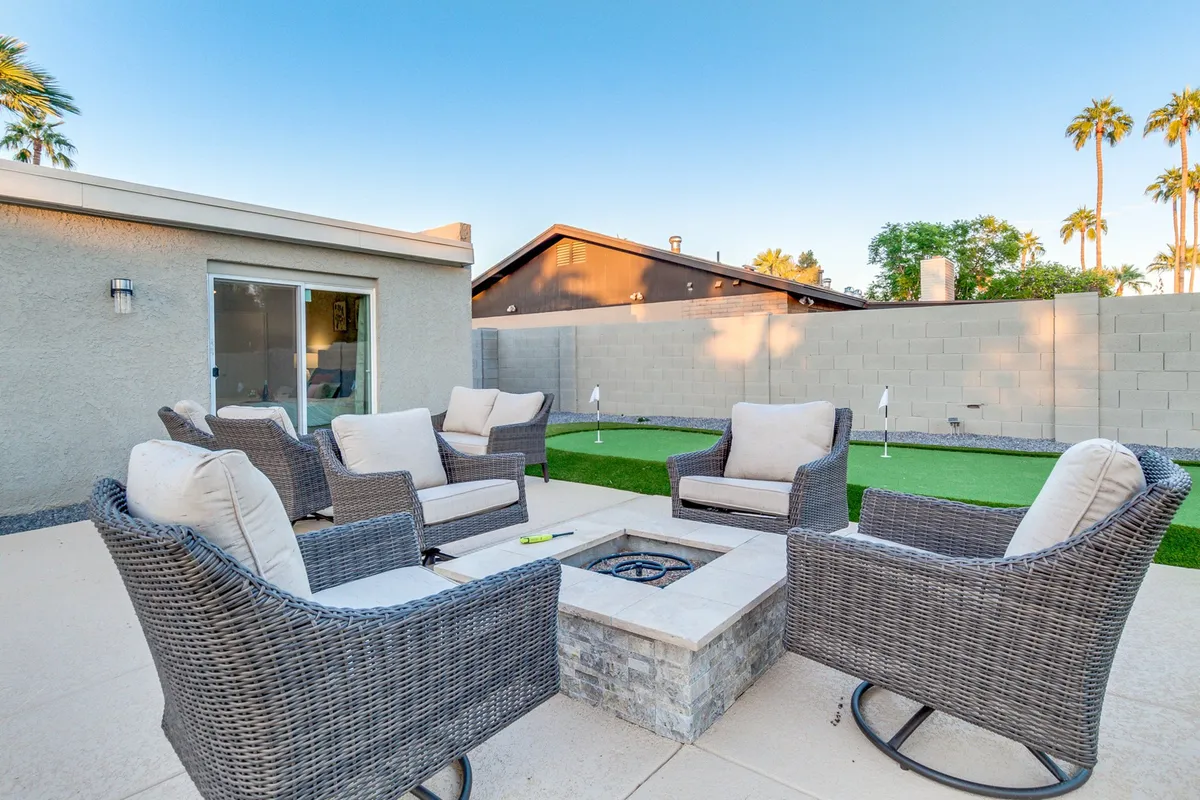 A beautifully landscaped green lawn centers on a fire pit surrounded by comfortable seating. The space offers plenty of room for socializing, enjoying evening conversations, or playing games on the lawn, making it ideal for group activities and relaxation.