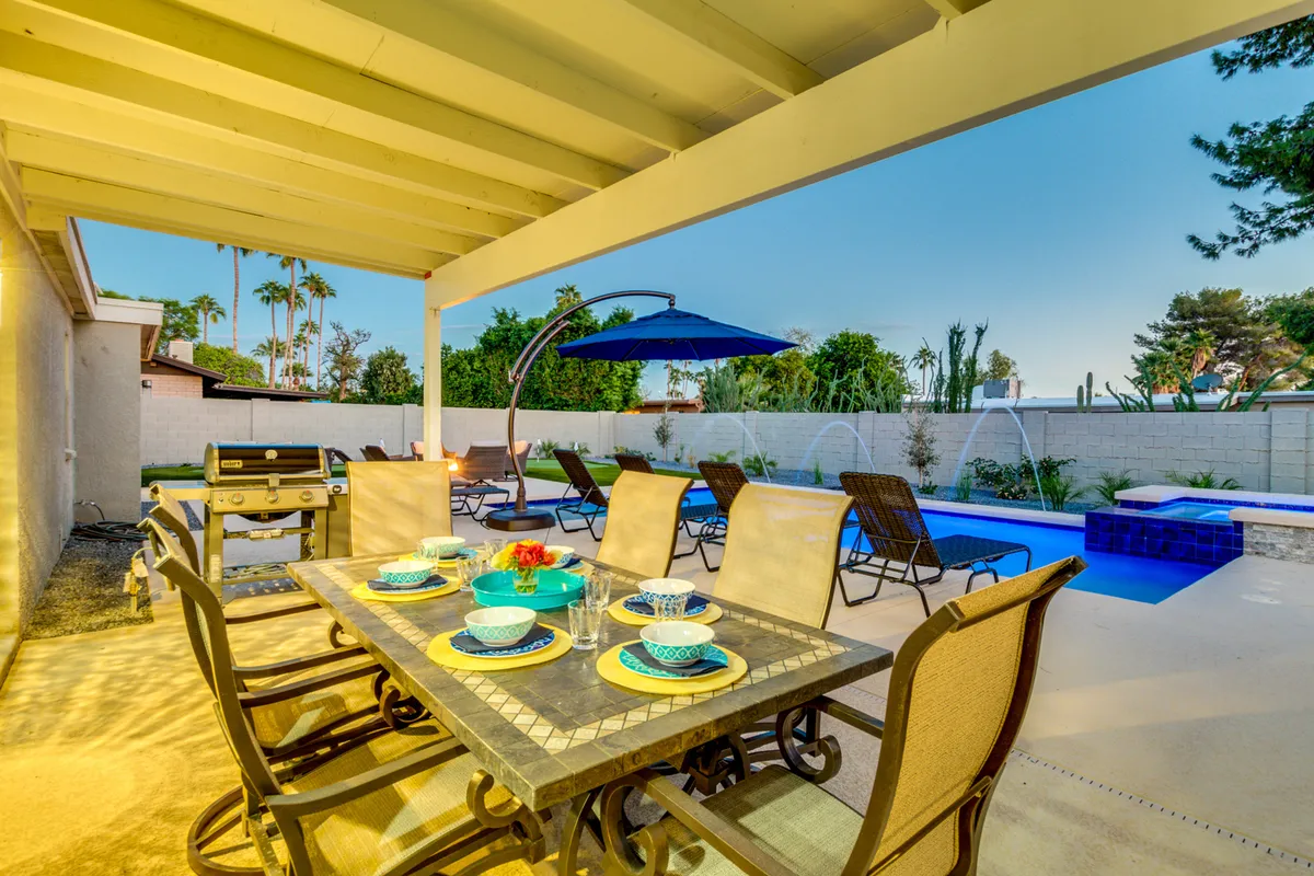 An inviting outdoor dining area overlooking the pool, set for a casual meal or evening gathering. The space is perfect for al fresco dining, socializing, and enjoying the warm Scottsdale evenings in style.